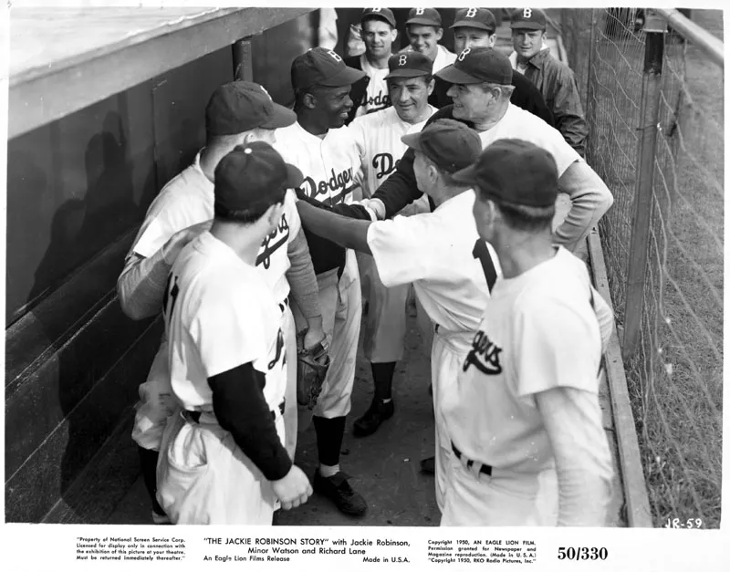 [Film still from The Jackie Robinson Story showing Jackie Robinson (as himself) with fellow Dodgers in the dugout]
