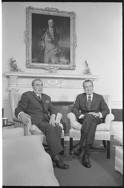 [President Richard Nixon and Soviet leader Leonid Brezhnev seated in the White House, portrait of George Washington in the background]