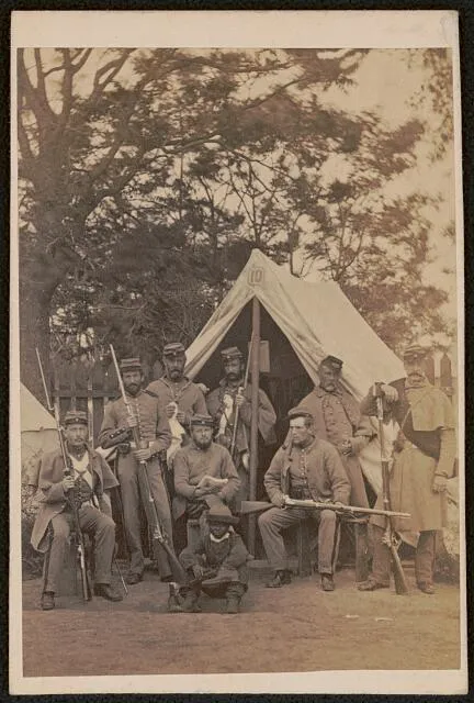 [Union soldiers with rifles stand in front of tent 