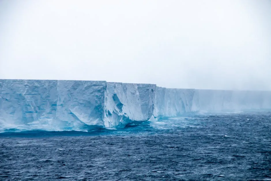 A breathtaking view of a massive iceberg in Antarctica surrounded by mist and cold ocean waters.