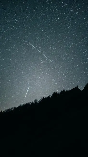 A breathtaking view of a star-filled sky over silhouetted mountains in Mont-Dore, France.