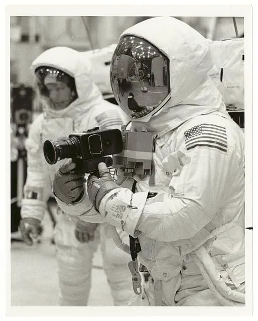 Apollo 11 Spacecraft Commander Neil Armstrong (front) and Lunar Module Pilot Edwin E. Aldrin (rear) practice lunar surface mobility at the Manned Spacecraft Center, Houston Armstrong has a camera attached to the chest area of the space suit. This method of attaching the camera is under study. The astronauts are in pressurized space suits /
