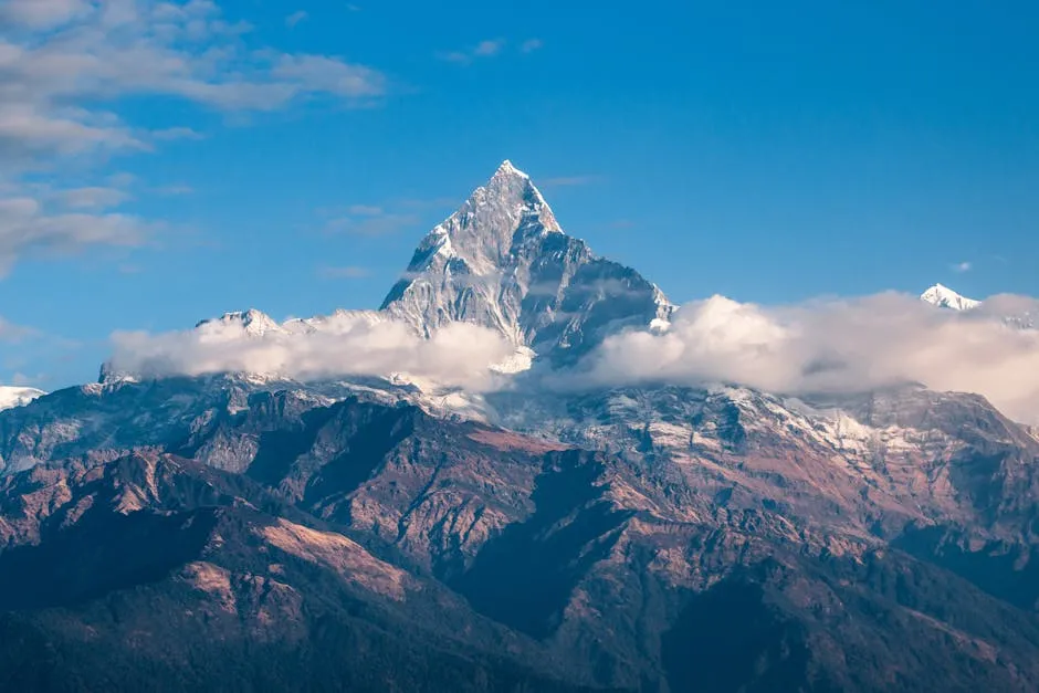 Breathtaking view of a snow-covered mountain peak surrounded by clouds during sunrise.