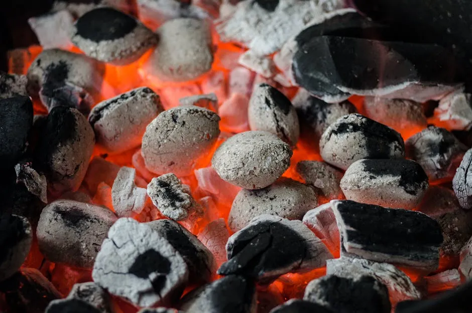 Close-up of glowing charcoal briquettes ready for outdoor barbecue grilling.