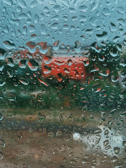 Closeup of glass window with waterdrops with countryside on background on rainy autumn day
