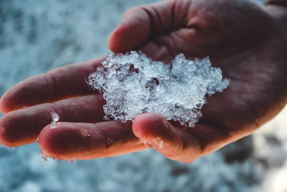 Detailed close-up of a hand holding ice outdoors, showcasing winter cold and texture.