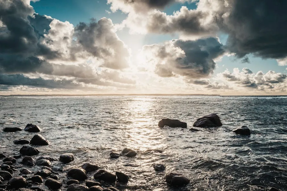 Dramatic sunrise over the Baltic Sea with rocky shoreline and scattered clouds creating a stunning view.