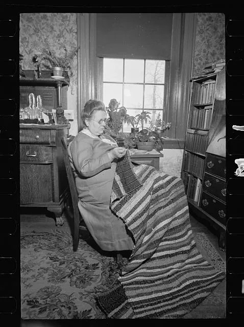 Homewoven dress and rug, Westmoreland Homesteads, Mount Pleasant, Westmoreland County, Pennsylvania. Westmoreland homesteader wearing dress of cloth woven herself on homestead looms and working on rug woven by her homestead loom