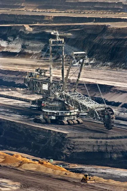 Large bucket wheel excavator operating in an open-pit mine with layered soil and coal.