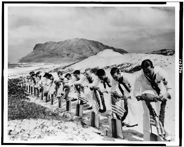 Seamen at Kaneohe Naval Air Station decorate the graves of their fellow sailors killed at Pearl Harbor, December 7, 1941