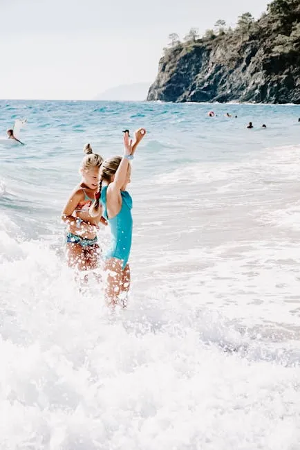 Two children having fun in ocean waves on a sunny summer beach day.
