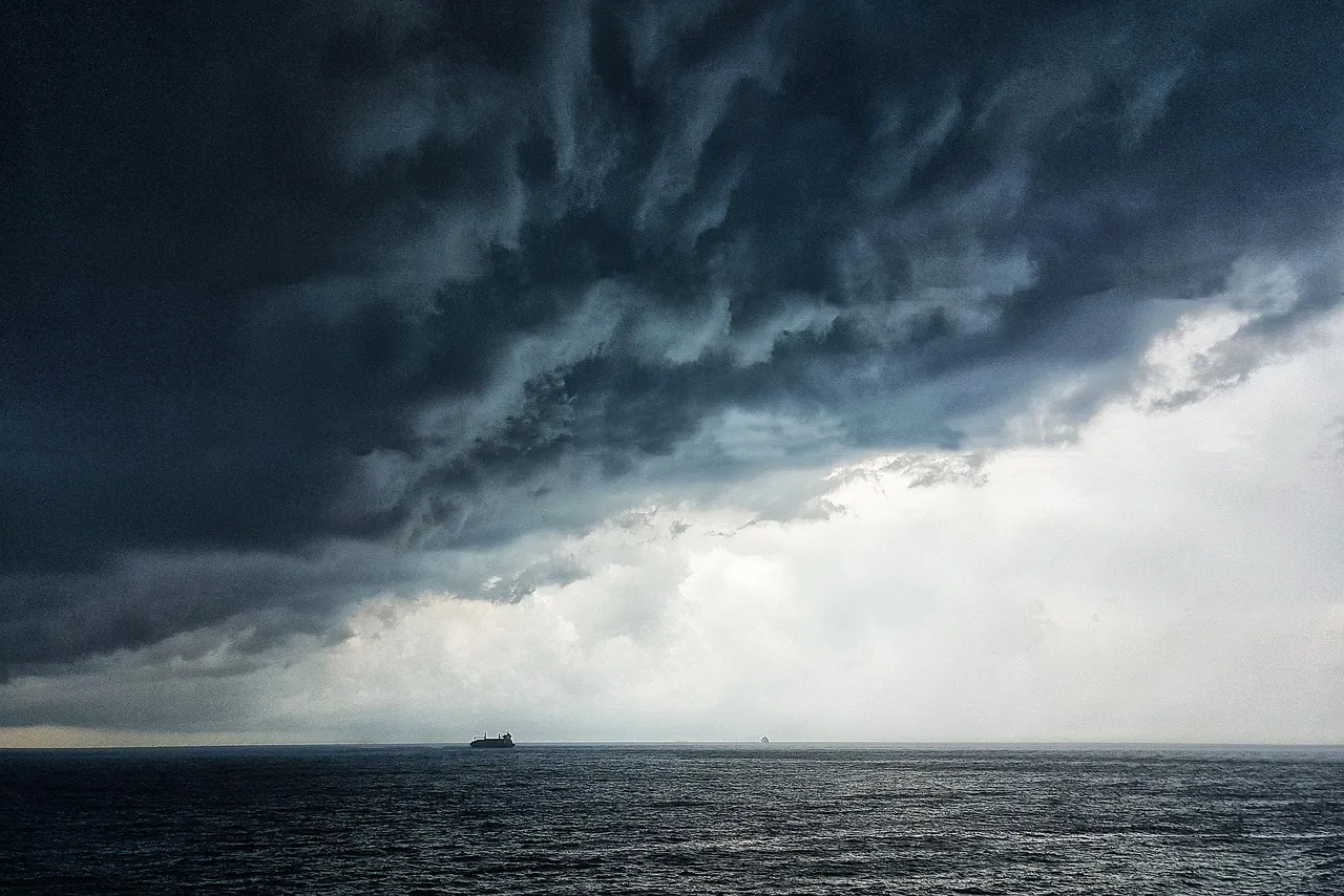 Dark, dramatic storm clouds hanging low over the vast, open ocean.