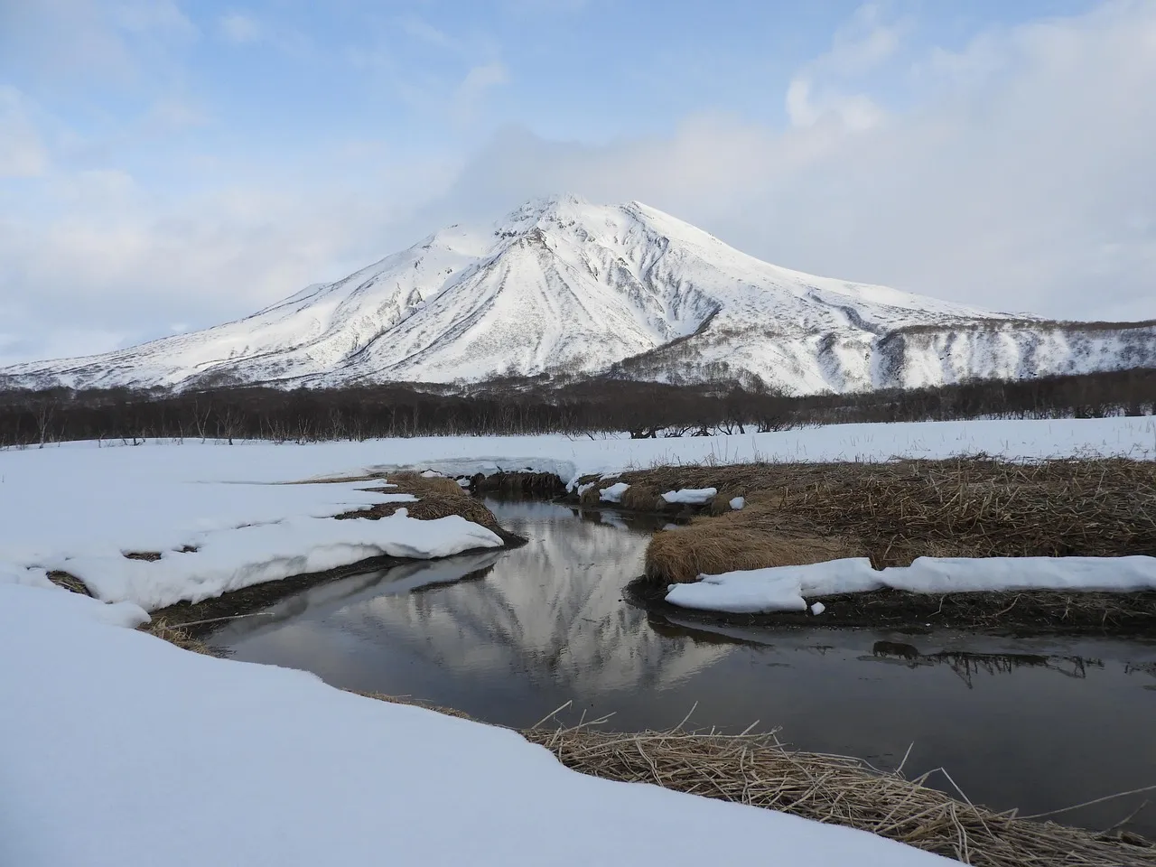 Snow-covered mountain and stream representing frozen and liquid surface freshwater sources.